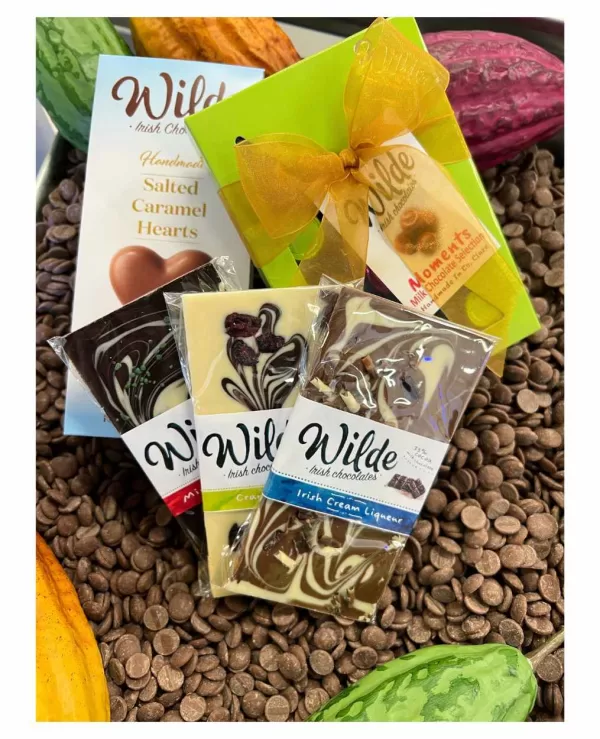 A Taste of Wilde chocolate gift hamper products are displayed on a bed of chocolate drops.