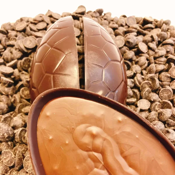 Dark chocolate praline filled Easter egg displayed on a bed of chocolate drops.