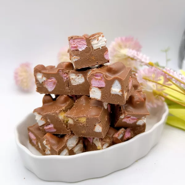 Rocky Road bites are displayed in a serving dish with flowers in the background.