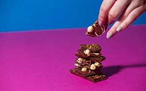 Hazelnut chocolate mountain on blue and pink background.