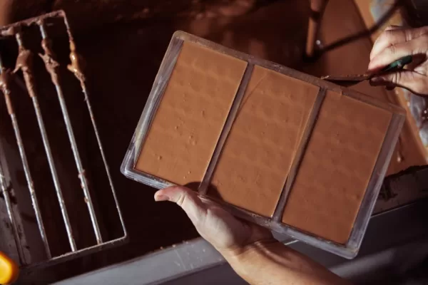 An employee places the chocolate into a mould and scrapes the edges clean.