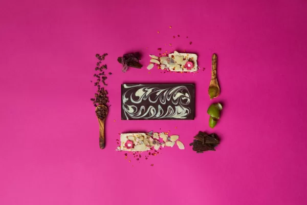 Dark Chocolate Seaweed & Lime Oil Splash chocolate bar displayed on a pink background with individual ingredients surrounding.