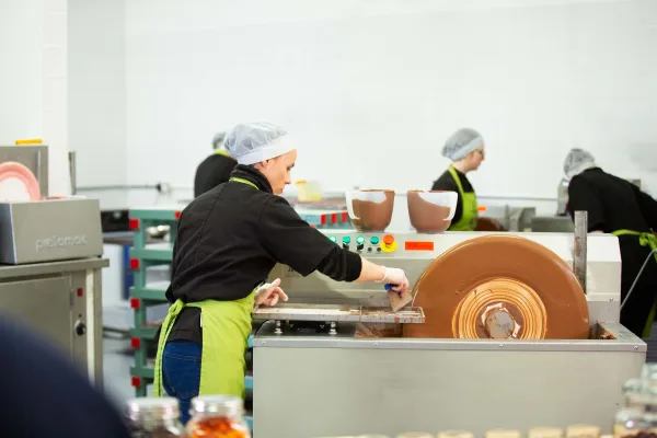 Wilde Irish Chocolates Factory Behind the Scenes with chocolatiers working with chocolate tempering machine.