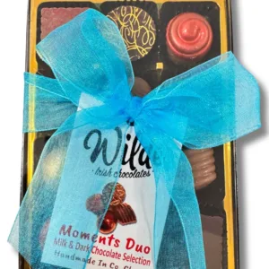 Decorated milk and dark chocolates in a box tied with a blue ribbon bbow and a gold interior