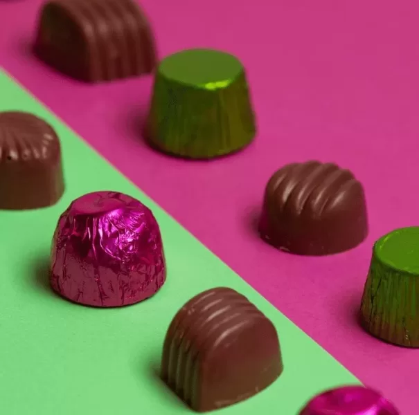 Chocolates are displayed on a pink and green background.